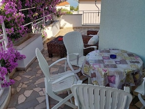A patio with white chairs and a table covered with a patchwork tablecloth.