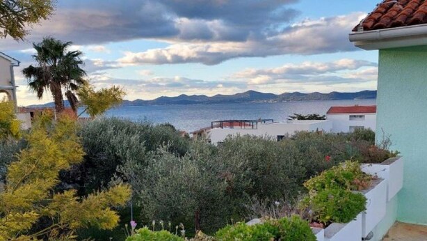 Vista costera con un jardín en primer plano y el mar al fondo.