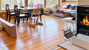 Interior acogedor de una cabaña con suelo de madera, una mesa de comedor con sillas, un sofá y una chimenea.