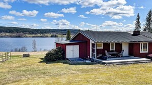 Una casa roja con garaje, un porche cubierto y vista a un lago.