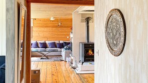 Un salón acogedor con suelo de madera, un sofá con cojines, una chimenea y un plato decorativo en la pared.