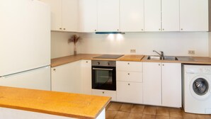 A compact kitchen with white cabinets, a built-in oven, a washing machine, and a wooden countertop. - Charming Holiday Home in Clavier With Garden (Clavier)