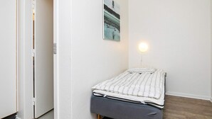 Un dormitorio pequeño y ordenado con una cama individual, una mesita de noche y una lámpara de pared.