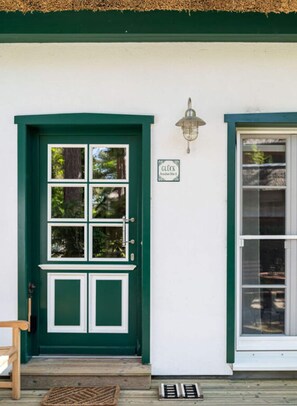 A green door with a white frame, a small sign above it, and a wooden bench outside. - Beach House Dune 19 - Happiness (Ostseebad Dierhagen)
