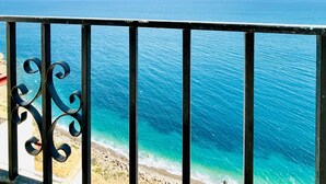A balcony with a metal railing overlooking a beach and the ocean.