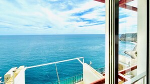 A balcony with a view of the sea and a coastal landscape.