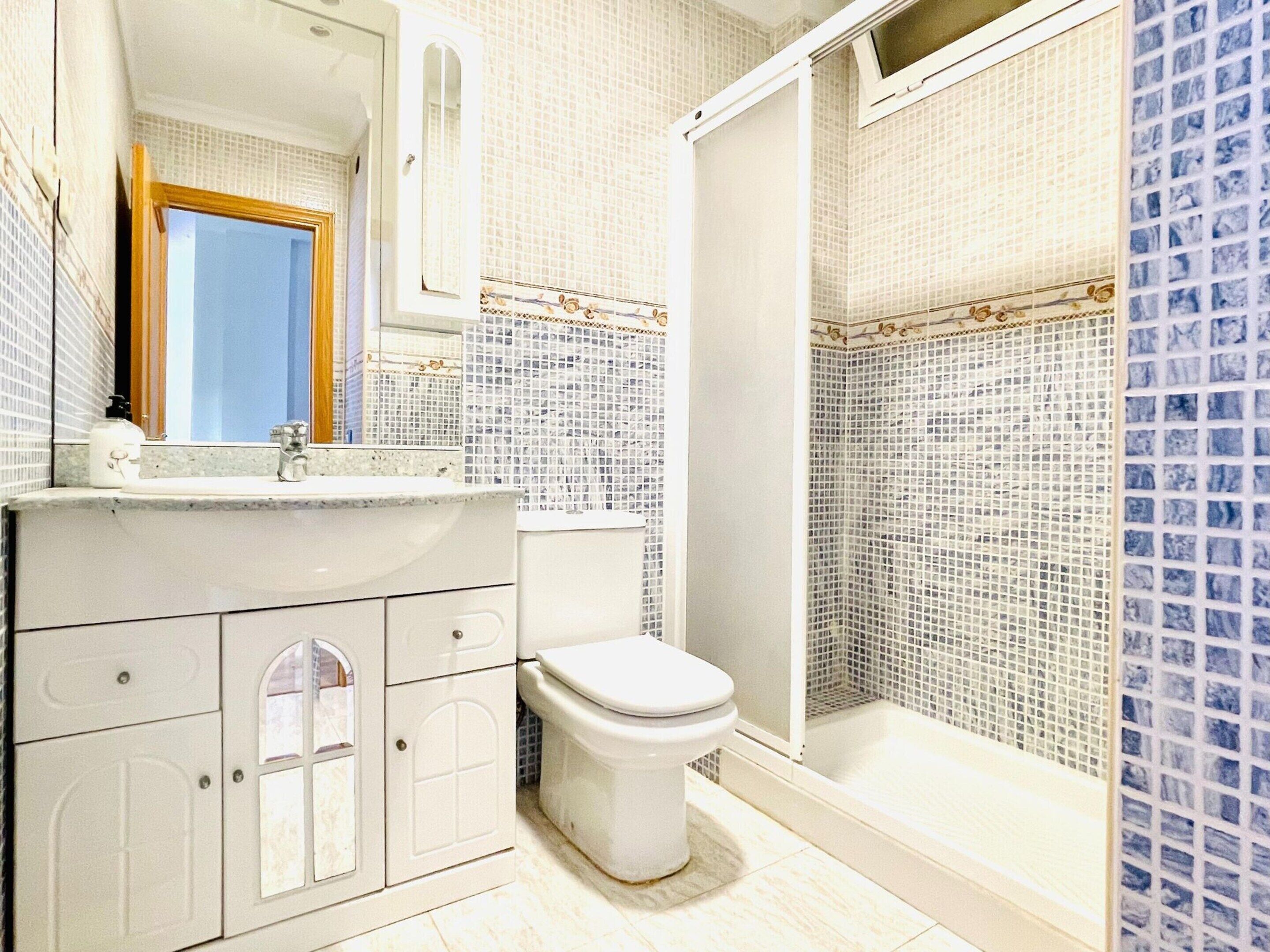 Un baño con un lavamanos blanco, un inodoro y una zona de ducha.