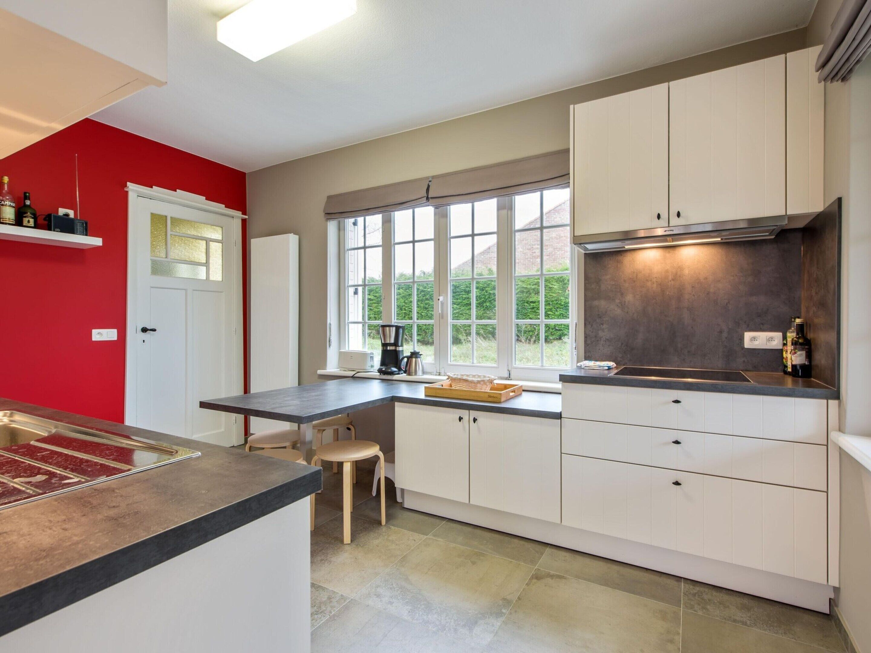 A modern kitchen with white cabinets, a black countertop, and a window providing natural light.