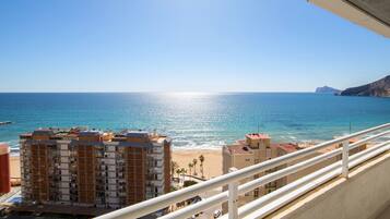 Une vue sur la côte depuis un balcon, avec un ciel dégagé, une plage et des bâtiments au premier plan.