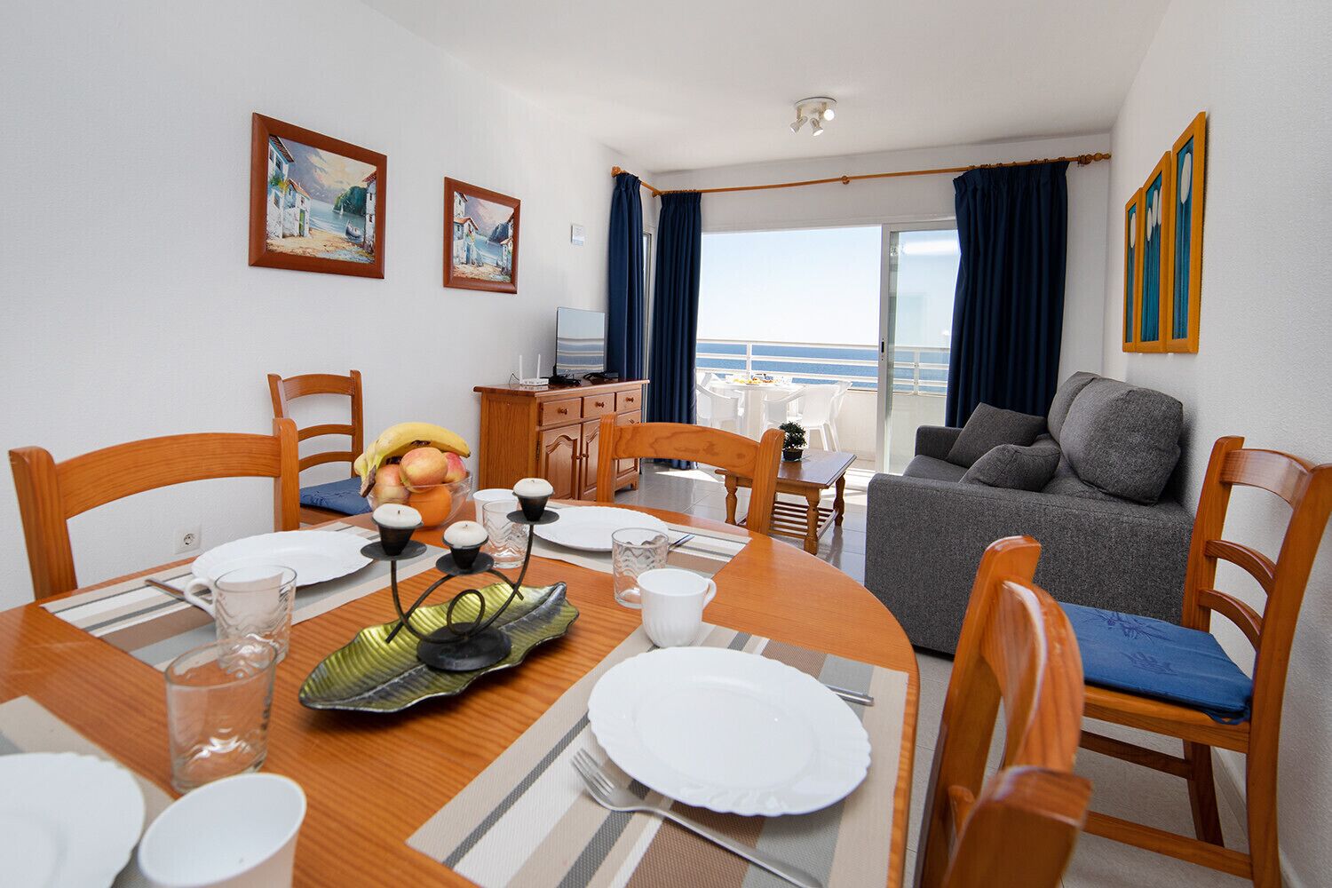 A dining area with a table set for four, a sofa, and a balcony with a view.