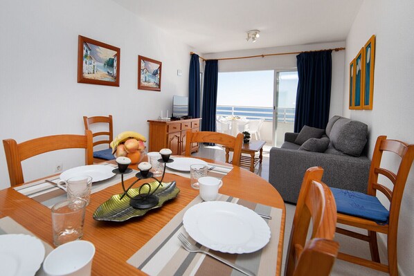 Un coin repas avec une table dressée pour quatre personnes, un canapé et un balcon avec vue.