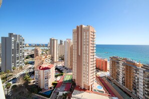 A high-rise building with multiple balconies, a rooftop pool, and a view of the ocean.