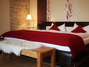 A bedroom with a large bed, a wooden bench, a lamp, and a wall with decorative elements. - Kiesenberg 9 Comfortable Holiday Residence (Thanstein)