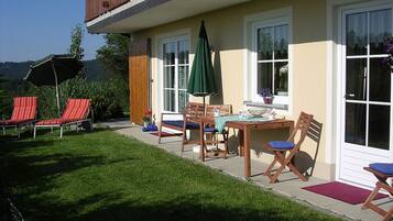 A two-story house with a balcony, a patio with outdoor furniture, and a well-maintained lawn.