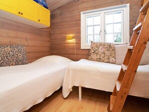 A cabin with two beds, wooden walls, a window, and a yellow cabinet. - 7 Person Holiday Home in Hojby (Hojby)