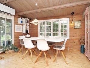 A wooden interior with a dining table, chairs, and a large window. - 7 Person Holiday Home in Hojby (Hojby)