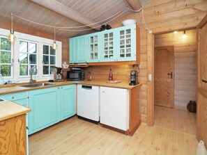 A kitchen with teal cabinets, a microwave, a coffee maker, and a dishwasher. - 7 Person Holiday Home in Hojby (Hojby)