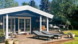 A modern house with a deck, outdoor seating, and potted plants. - 7 Person Holiday Home in Hojby (Hojby)