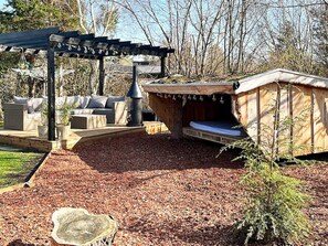 A patio area with a pergola, outdoor seating, and a wooden structure with a bench. - 7 Person Holiday Home in Hojby (Hojby)