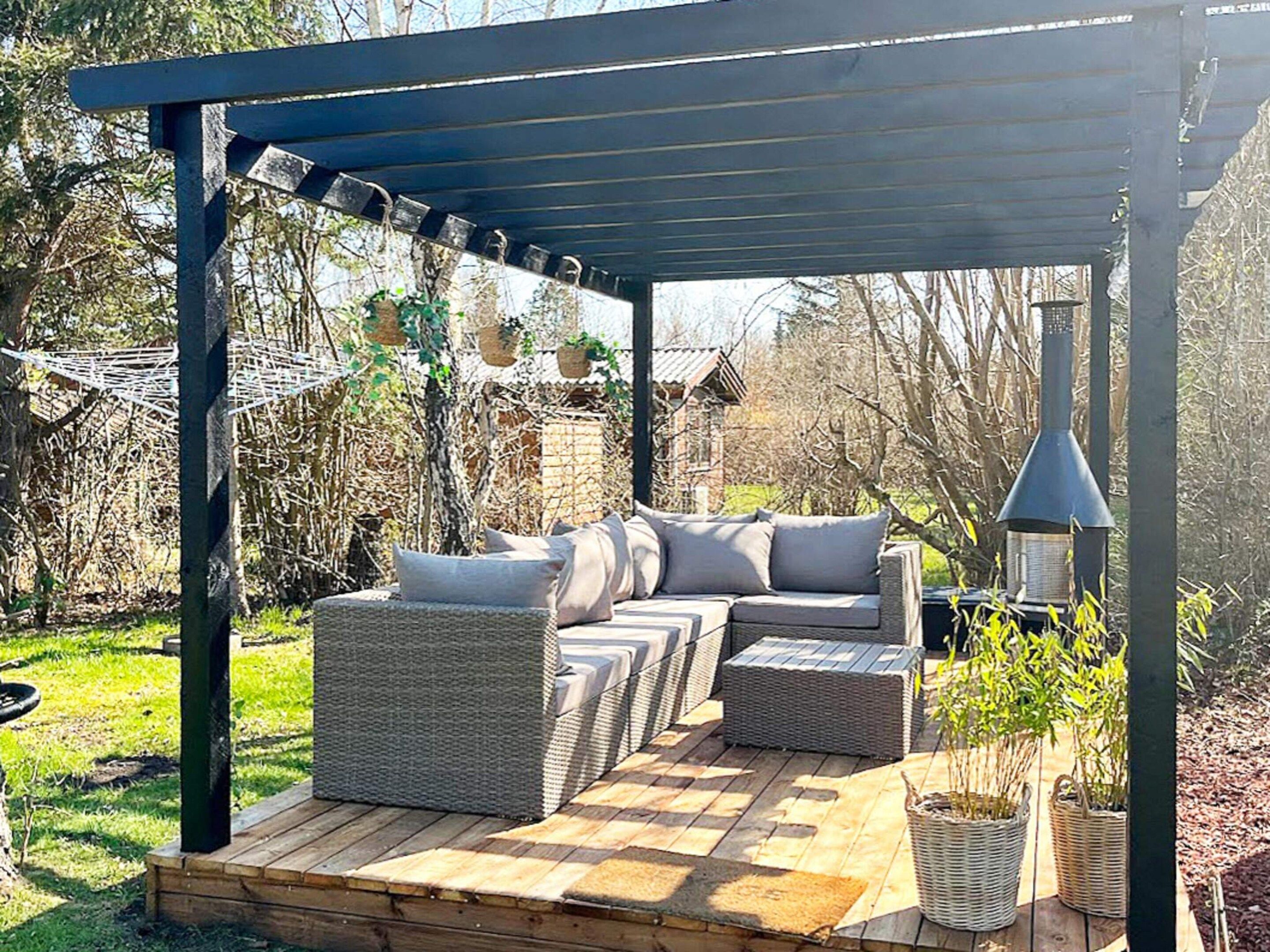 A covered outdoor seating area with a built-in grill and a pergola overhead.