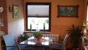 Un comedor con pared de ladrillo, un ventanal grande y una mesa con sillas.