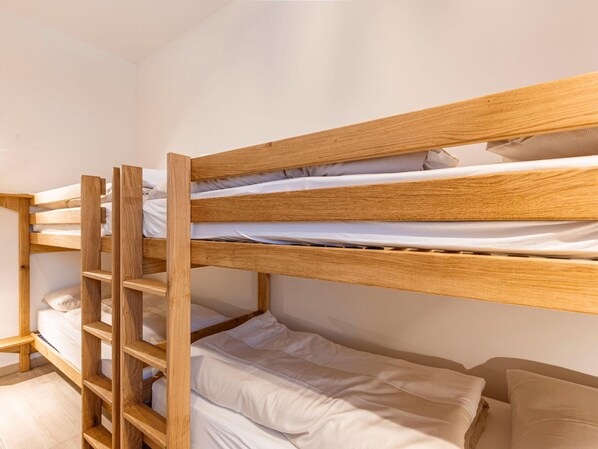 Una cama litera con estructura de madera y ropa de cama blanca.