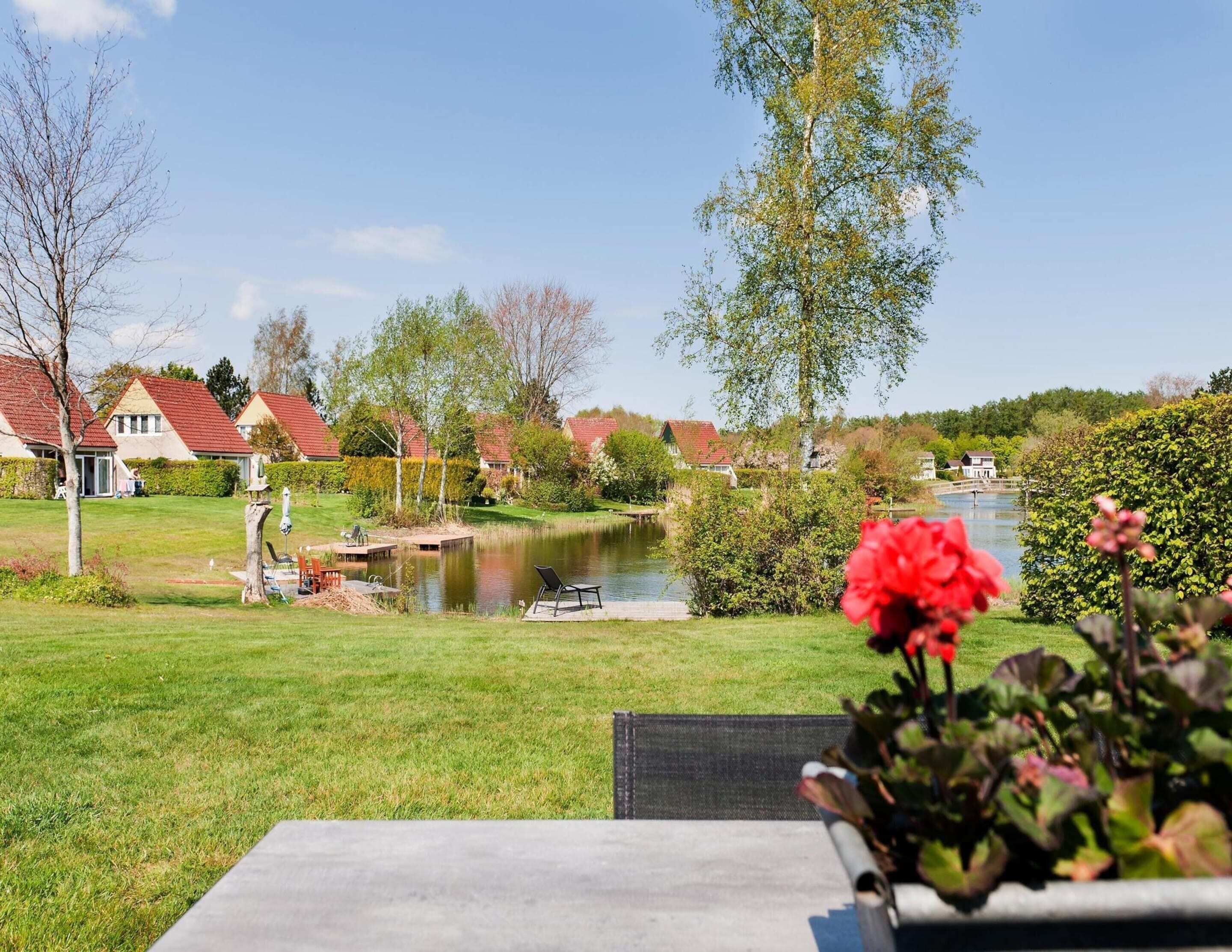Uitzicht op een meer met huizen, een steiger en een gazon.