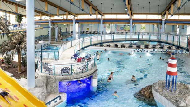 Piscina interior com escorrega, várias pistas de natação e posto de salva-vidas.