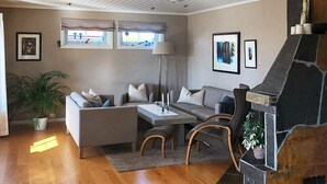 Una sala moderna con chimenea, un conjunto de sofás, una mesa de comedor y una planta en maceta.