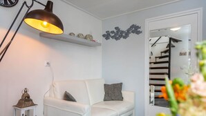 Ein modernes Wohnzimmer mit einem weißen Sofa, einer schwarzen Stehlampe, einem kleinen Beistelltisch und einer dekorativen Laterne.