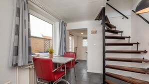 Ein Essbereich mit Tisch und Stühlen, eine Treppe und ein Blick ins Freie.