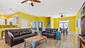 A spacious living room with a brown leather sofa, a wooden coffee table, and a dining area with a table and chairs. - 6BR North Myrtle Beach House with private pool and loads of fun (North Myrtle Beach)