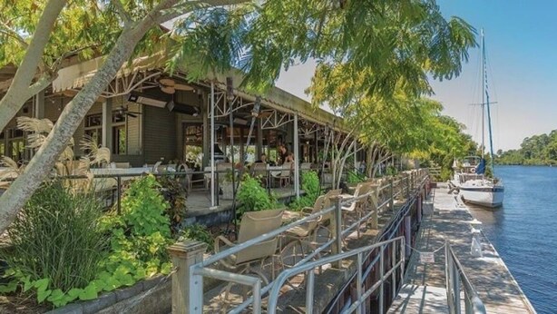 A waterfront restaurant with outdoor seating, a dock, and a sailboat. - 6BR North Myrtle Beach House with private pool and loads of fun (North Myrtle Beach)
