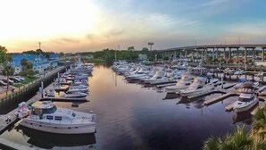 A marina with numerous boats docked, a bridge in the background, and a calm water body. - 6BR North Myrtle Beach House with private pool and loads of fun (North Myrtle Beach)