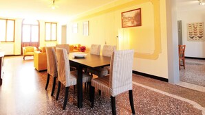 A dining area with a long table, six chairs, and a sofa. - Apartment in Valbelluna Near Dolomites (Santa Giustina)