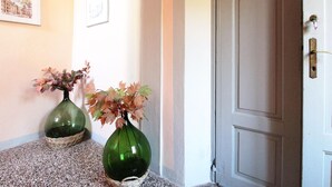 A hallway with two green vases on a granite countertop, a door with a brass handle, and a wall-mounted light fixture. - Apartment in Valbelluna Near Dolomites (Santa Giustina)