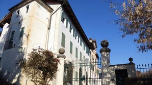 A historic building with a white facade, green shutters, and a gated entrance. - Apartment in Valbelluna Near Dolomites (Santa Giustina)