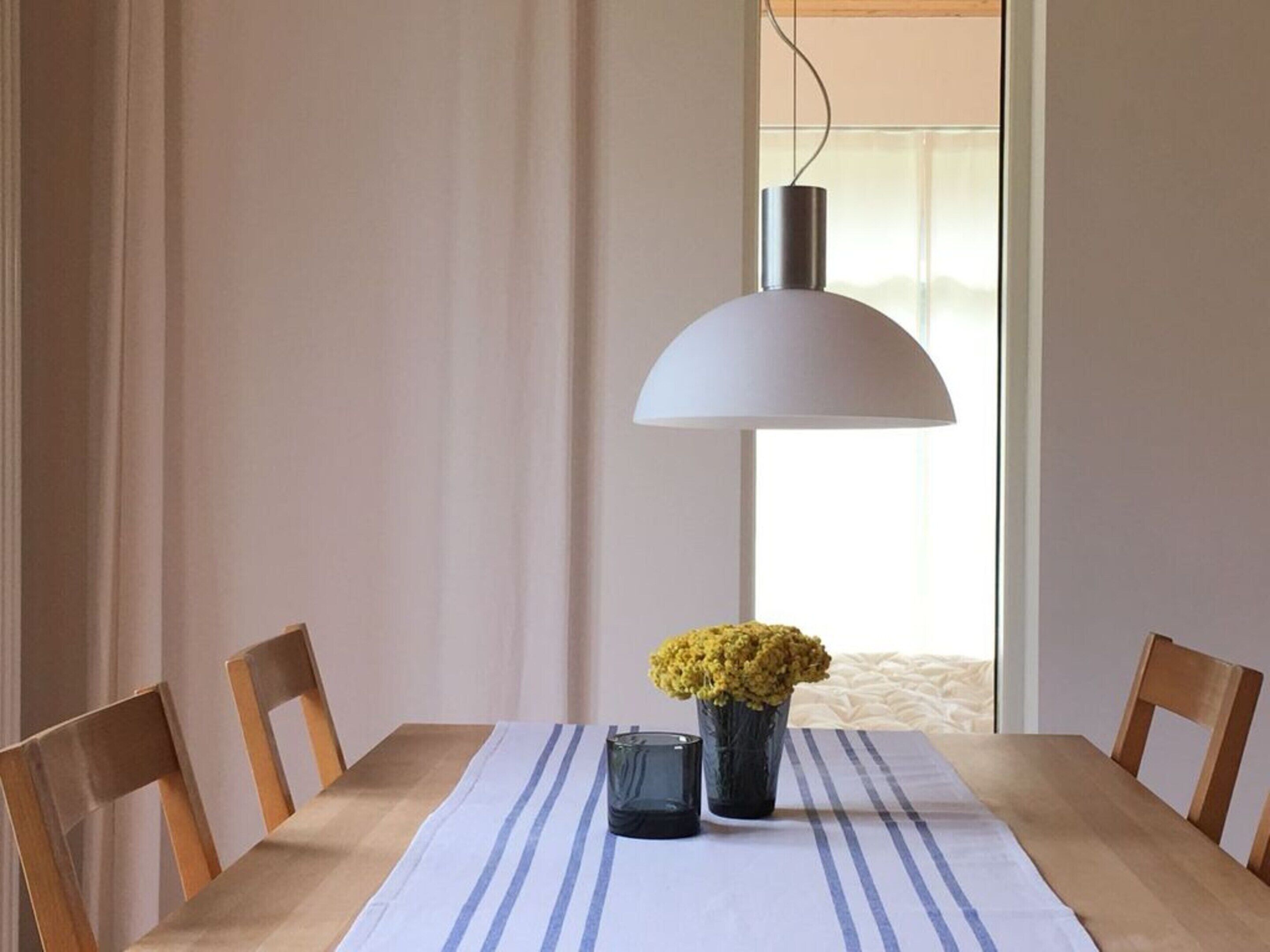 A dining table with a white tablecloth and a vase of yellow flowers.