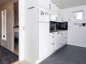 A compact kitchen with white cabinets, a black countertop, and a built-in sink. - 4 Star Holiday Home in Juelsminde (Juelsminde)