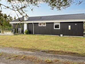A single-story building with a dark exterior, a flat roof, and a small front yard. - 4 Star Holiday Home in Juelsminde (Juelsminde)