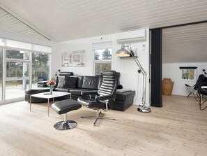 A modern living room with a black leather sofa, a black leather chair, a white coffee table, and a floor lamp. - 4 Star Holiday Home in Juelsminde (Juelsminde)