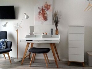 A modern room with a white desk, a black chair, a white cabinet, and a painting on the wall. - Holiday House House on Muhlfeldsee (Lobnitz)