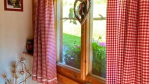 L’intérieur chaleureux d’un chalet avec un rebord de fenêtre en bois, une décoration en forme de cœur et un rideau à carreaux.