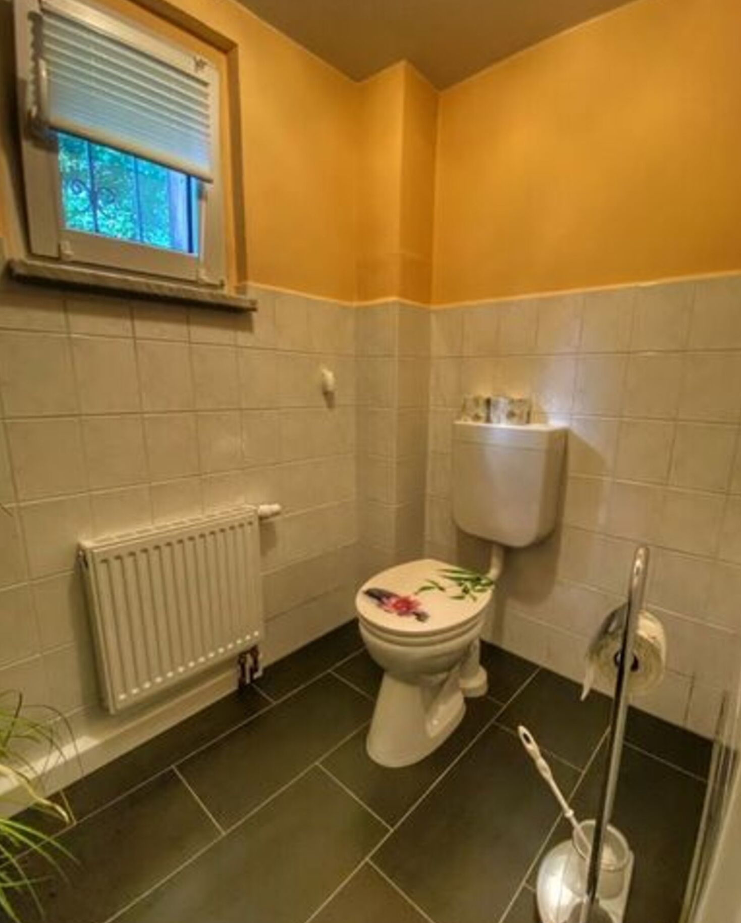 A bathroom with a toilet, a radiator, and a window.
