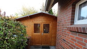 A wooden cabin with a brick exterior, a wooden door with glass panels, and a small porch area. - Wattloper Right Comfortable Holiday Residence (Wittmund)