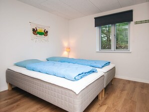 A bedroom with two beds, a window with a view of trees, a lamp, and a wall decoration. - 8 Person Holiday Home in Blavand (Blavand)