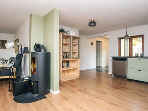 A modern living room with a fireplace, a kitchen with a dishwasher, and a dining area with a table and chairs. - 8 Person Holiday Home in Blavand (Blavand)