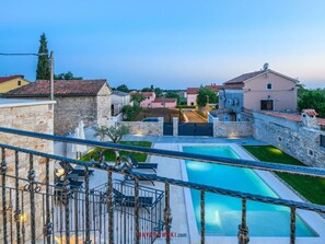 A pool area with stone walls and a view of surrounding buildings.