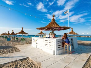 A beachside bar with thatched umbrellas, a tiled floor, and a view of the sea. - Residence With Swimming Pool Nearby the sea (Rimini)