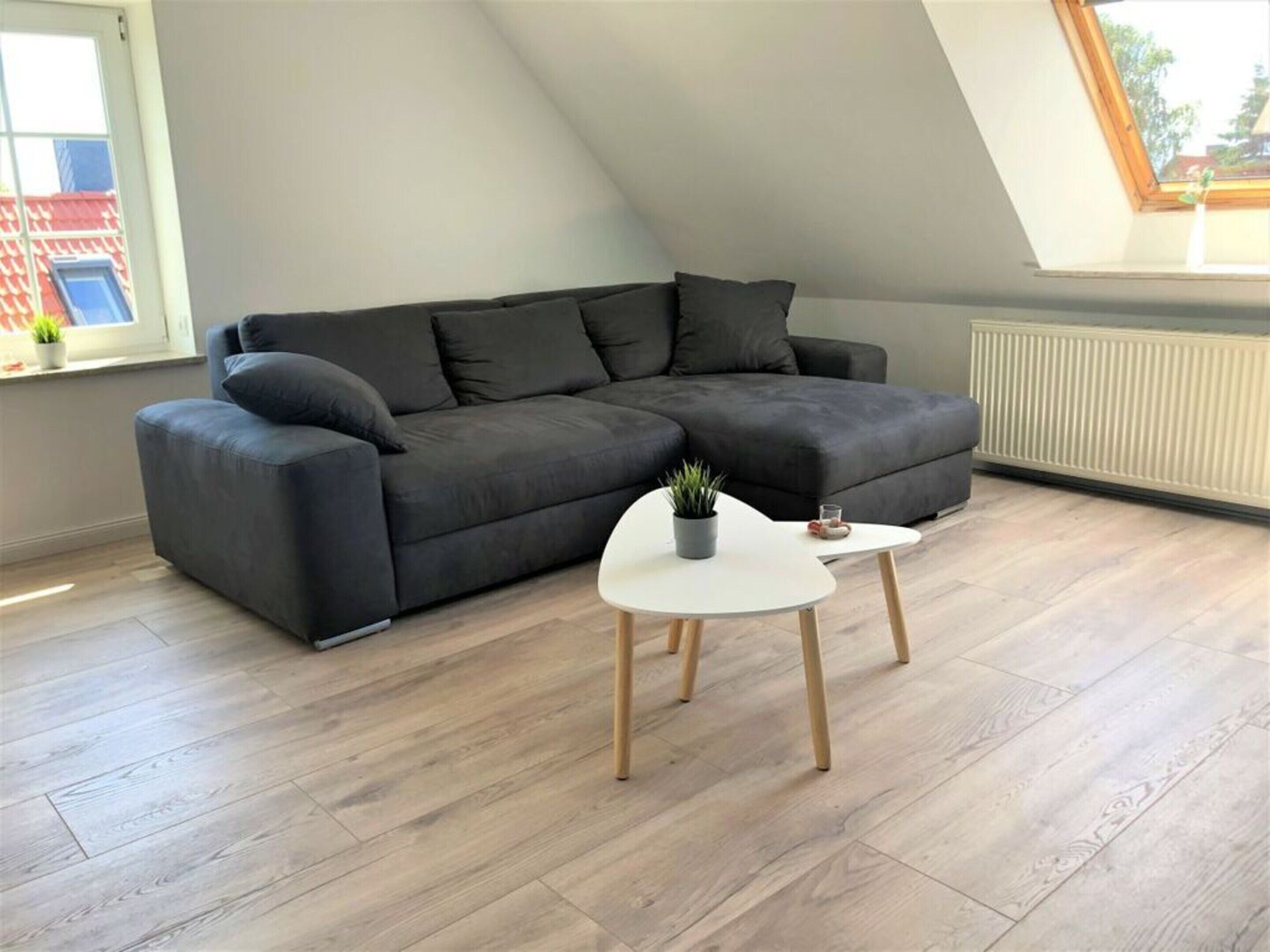 A modern living room with a sectional sofa, a small white table, and a potted plant.